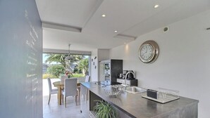 Una cucina moderna con una grande isola, elettrodomestici in acciaio inossidabile e un orologio a parete.