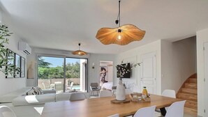 Un comedor moderno con mesa de madera, sillas blancas e iluminación colgante.