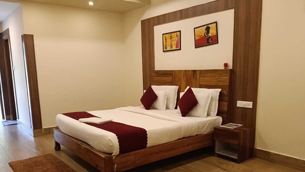 A neatly made bed with a wooden headboard, a brown rug, and two framed pictures on the wall.