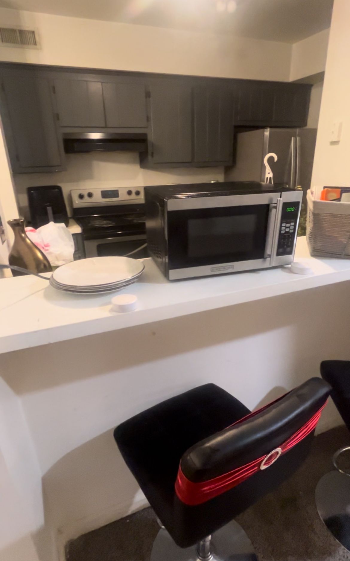 Una cocina con microondas, estufa y un taburete de bar.