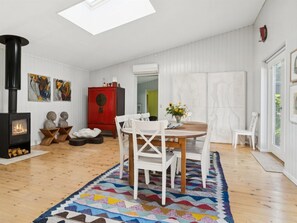 Ein modernes Wohnzimmer mit Kamin, weißen Wänden, einem roten Schrank und einem Essbereich mit weißen Stühlen.