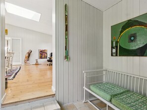 Ein Zimmer mit Holzboden, weißen Wänden, einer grün gemusterten Bank und einem farbenfrohen abstrakten Gemälde.