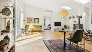 A modern living room with a yellow sofa, a dining table with chairs, a fireplace, and a bookshelf with decorative items. - "Verna" - 450m from the sea by Interhome (Ebeltoft)