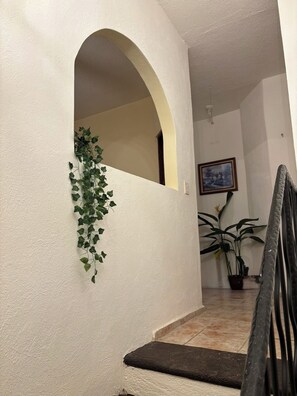 A staircase with a white wall, an archway, and a potted plant. - Del Sol Suite: Ideal for travelers who enjoy a quiet place to relax (Puerto Vallarta)