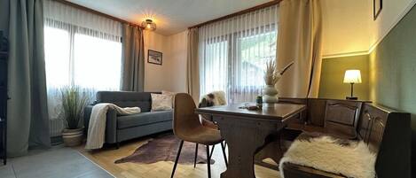 Ein modernes Wohnzimmer mit einer Couch, einem Esstisch und einer Lampe.