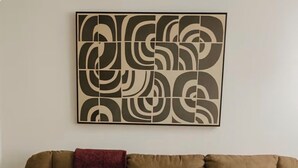 Ein Wohnzimmer mit braunem Sofa, einer roten Decke, einem weißen Kissen, einer kleinen Topfpflanze und einem Couchtisch mit grauem Tuch.