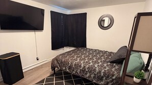 Ein Schlafzimmer mit einem Bett, einem Fernseher, einem Spiegel und einer kleinen Pflanze.