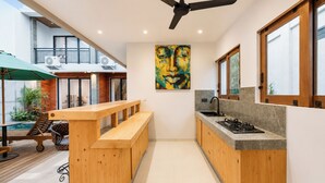 Una cocina moderna con un banco de madera, un ventilador de techo y un ventanal grande.