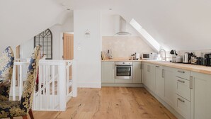 A modern kitchen with a skylight, wooden flooring, and a white railing. - Beautiful 3 Bedroom House in Oxfordshire (Souldern)