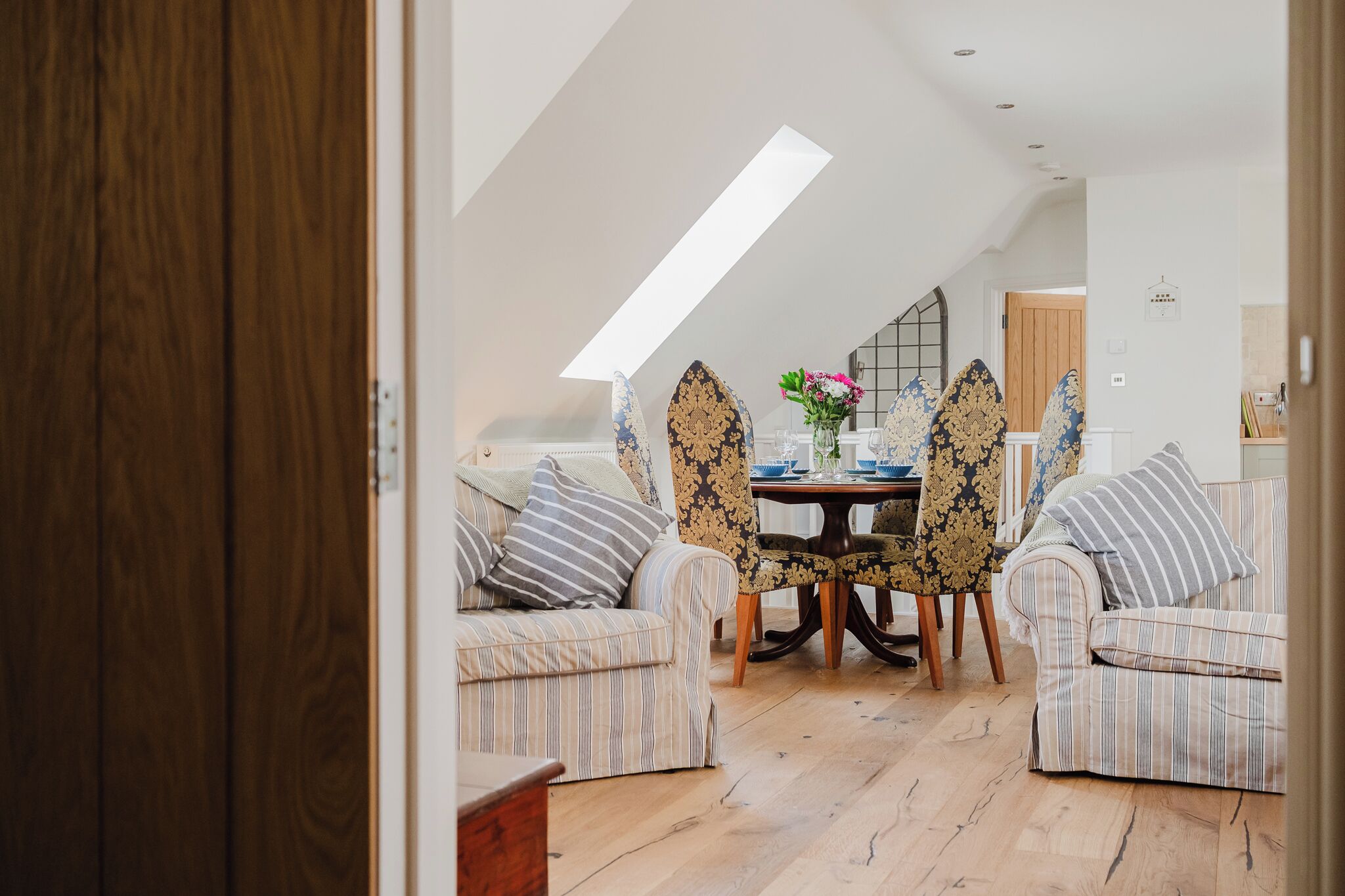 A cozy room with a high ceiling, a dining table with chairs, and a sofa.