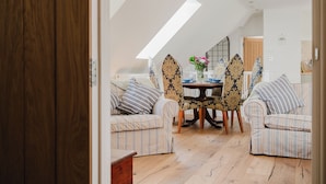 A cozy room with a high ceiling, a dining table with chairs, and a sofa. - Beautiful 3 Bedroom House in Oxfordshire (Souldern)