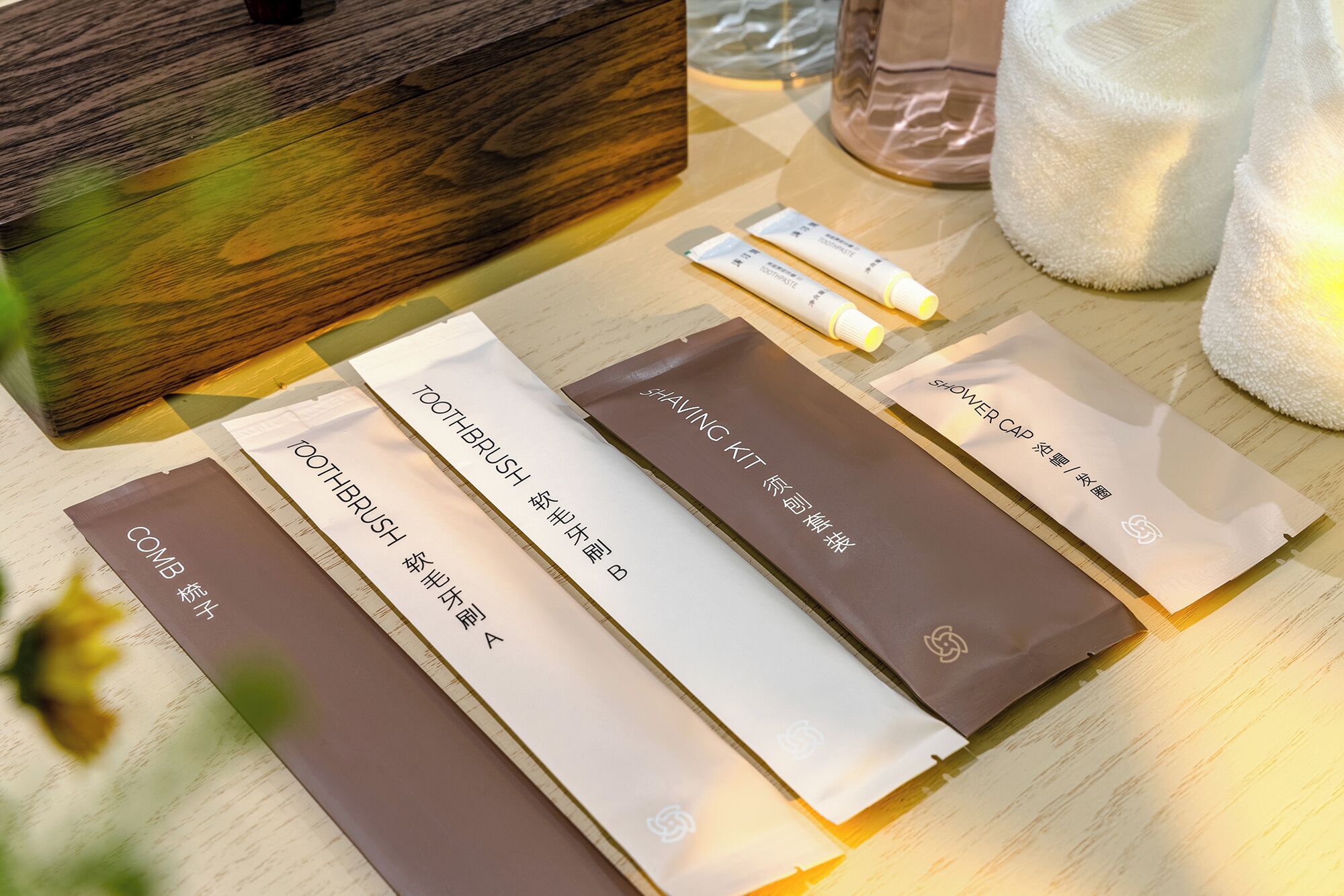 Une surface en bois sur laquelle sont disposés divers articles de toilette, notamment un peigne, une brosse à dents, un kit de rasage et un bonnet de douche.