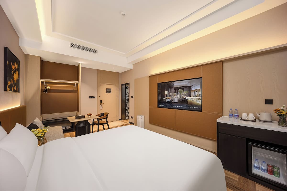 Ein Hotelzimmer mit Bett, Schreibtisch, Stuhl, Fernseher und Minibar.