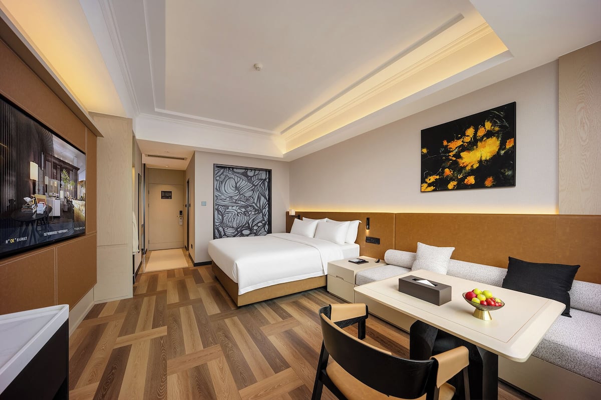 Ein Hotelzimmer mit Bett, Nachttisch, Stuhl und einer Essecke mit Tisch und Stühlen.