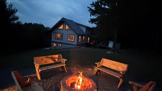 A house with a fire pit in the center surrounded by four wooden chairs.