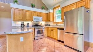 A modern kitchen with wooden cabinets, stainless steel appliances, and a granite countertop.