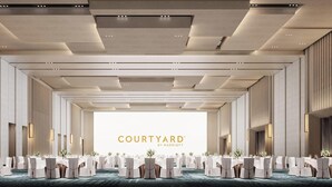 En rymlig bankettsal med trappstegsformade sittplatser, infälld belysning och en tydlig skylt med texten ”Courtyard by Marriott”.