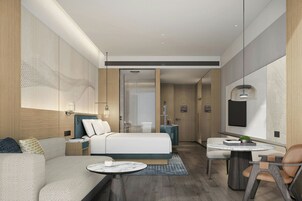 Una habitación de hotel moderna con cama, zona de estar y una pequeña mesa.