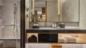 A modern bathroom with a glass shower enclosure, a vanity with a mirror, and a towel rack.