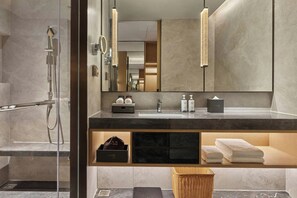 Een moderne badkamer met een douchecabine van glas, een wastafel met spiegel en een handdoekrek.