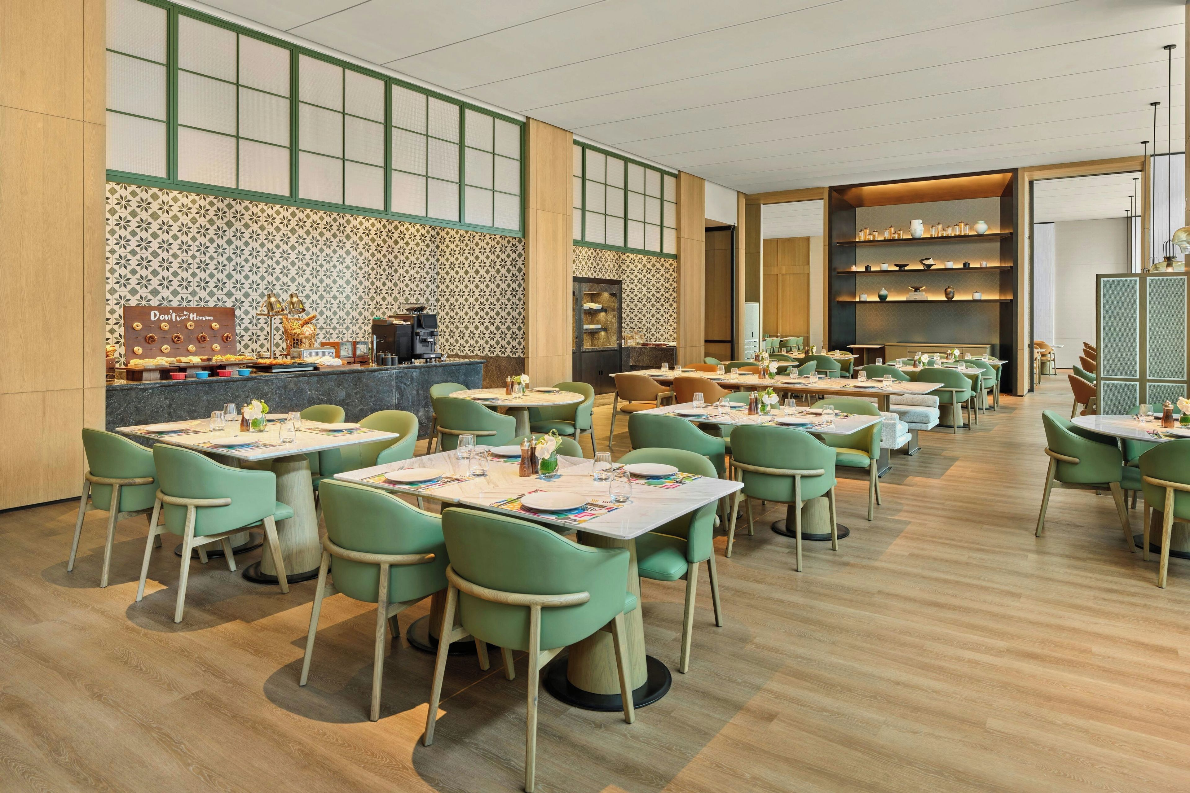 Un restaurante con varias mesas y sillas, una barra con una máquina de café y estantes con objetos decorativos.