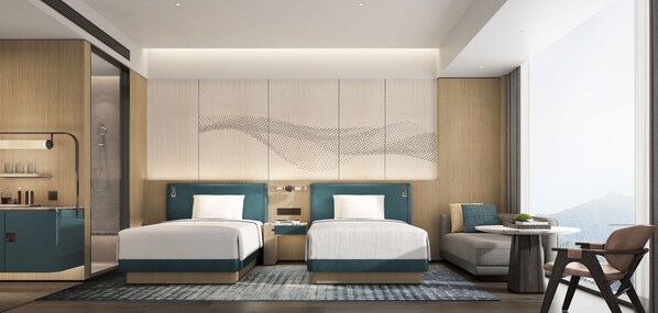 A modern hotel room with two beds, a small sofa, a round table, and a view of the mountains.