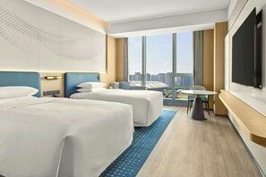 A hotel room with two beds, a desk, a chair, a TV, and a large window with a city view. - Courtyard by Marriott Rizhao (Rizhao)