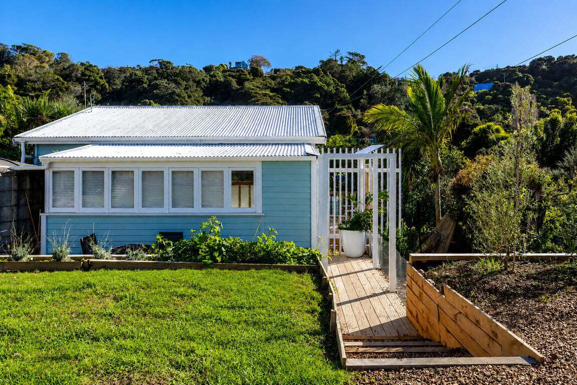 Una casa con fachada azul, un porche blanco y una terraza de madera.