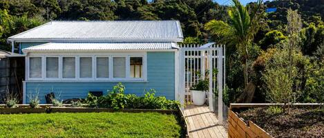 Una casa con fachada azul, un porche blanco y una terraza de madera.
