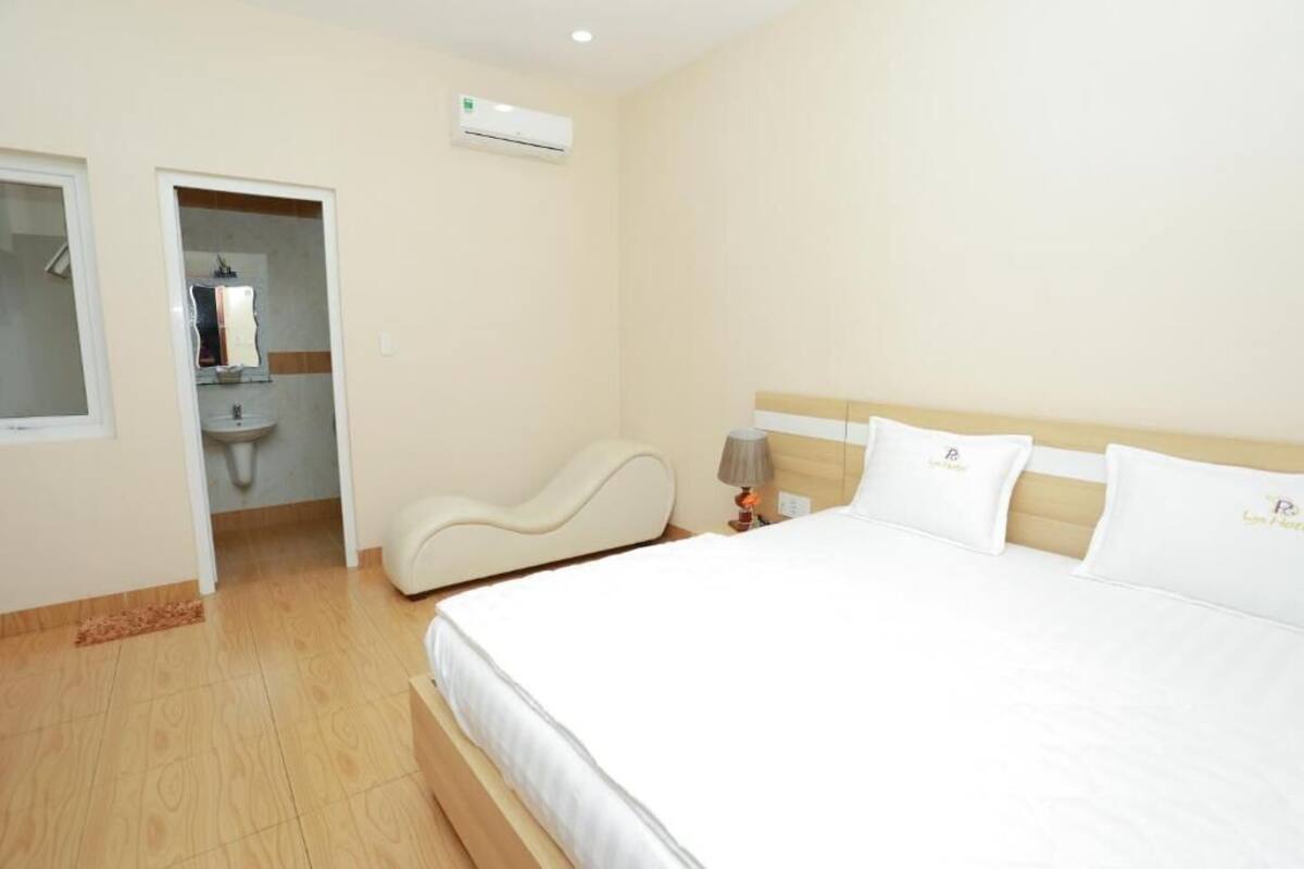 A hotel room with a bed, a bedside table with a lamp, a mirror, and a bathroom with a sink and toilet.