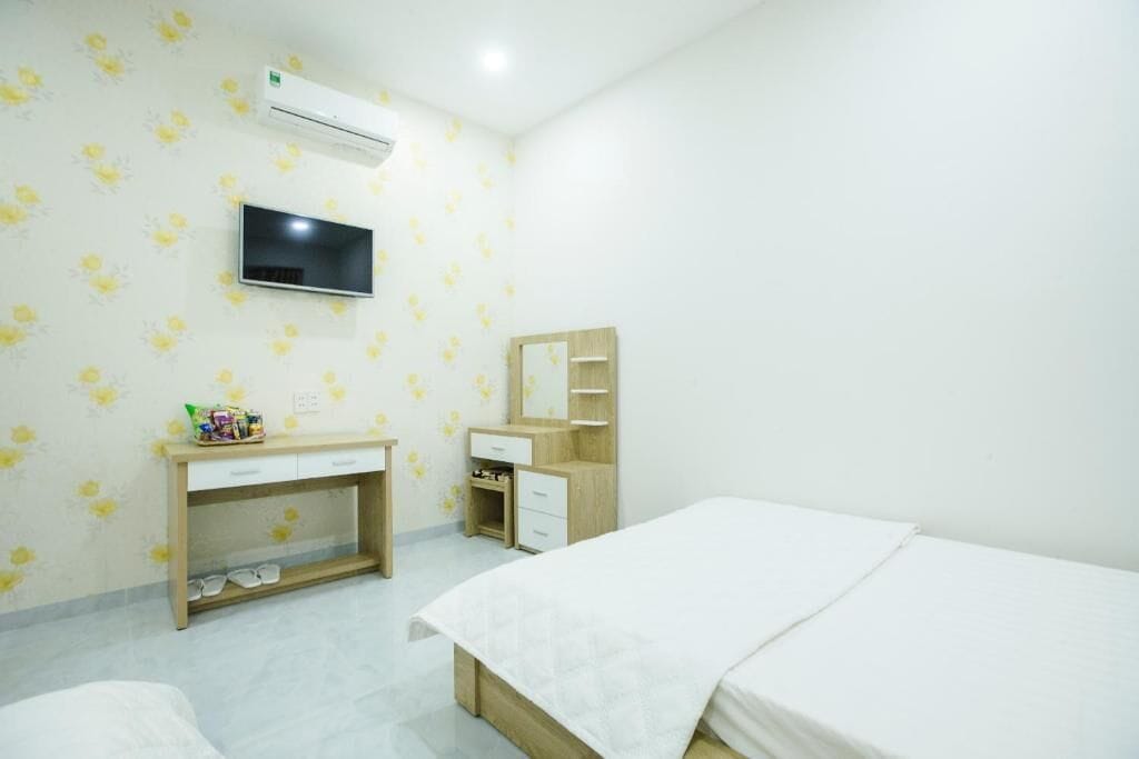 Un dormitorio con cama, escritorio, espejo y televisor.