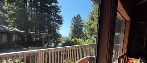 A wooden deck with a bench and table, overlooking a forested area.