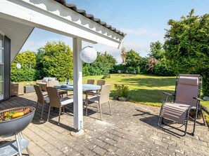 Un patio con mobiliario exterior, una parrilla y una pérgola.