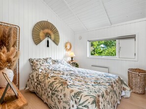 Un dormitorio con cama, ventilador de pared, ventana con vistas y cesta de mimbre.