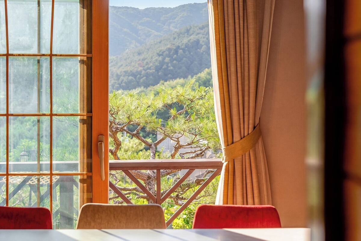 Habitación con vista a un paisaje montañoso a través de una ventana con marco de madera.