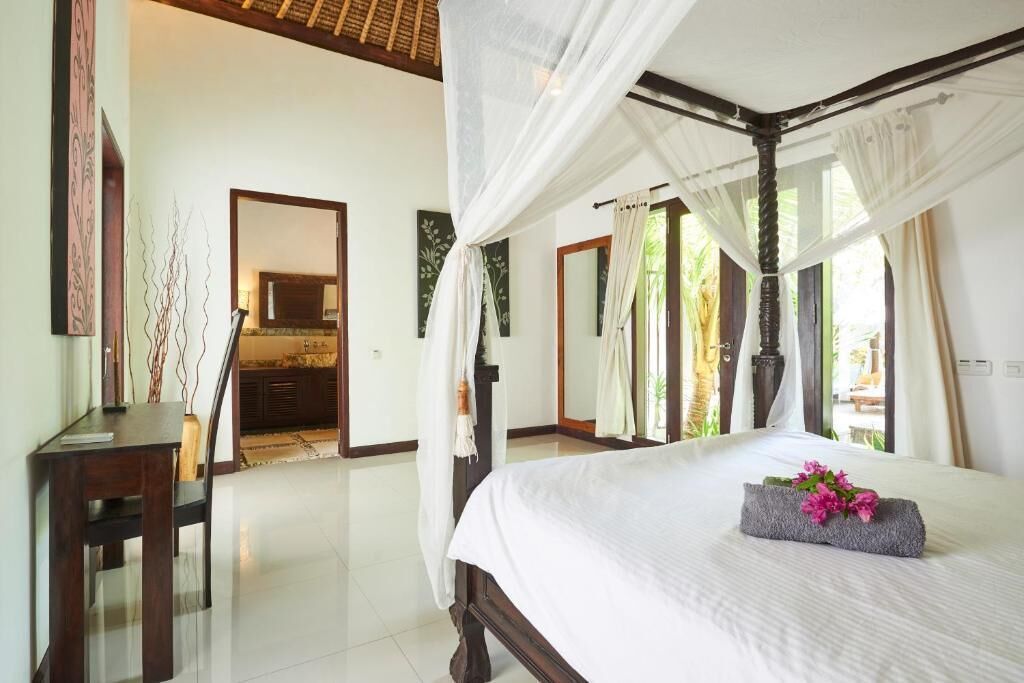 A bedroom with a four-poster bed, a desk, and a mirror.