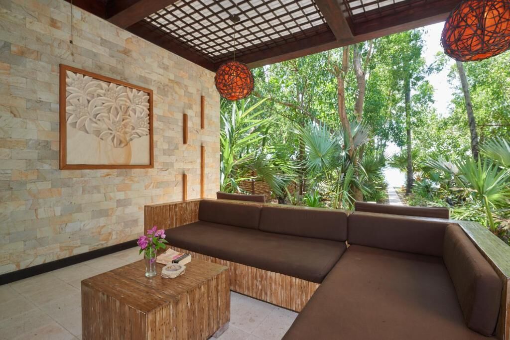 A modern outdoor seating area with a stone wall, a wooden coffee table, and a cushioned bench.