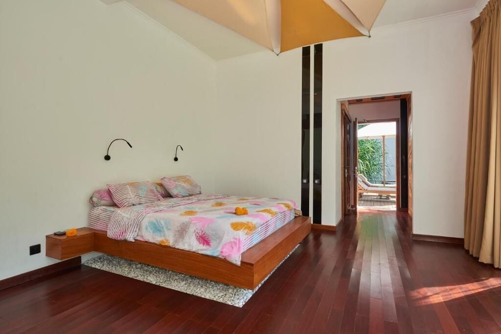 Une chambre à coucher avec un lit en bois, une petite table de chevet, un luminaire au plafond et une vue sur l’extérieur.