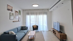 A modern living room with a sofa, coffee table, TV stand, and artwork on the walls. - Keren Home 3 bedr Karmei Gat Kiriat Gat (Kiriat gat)