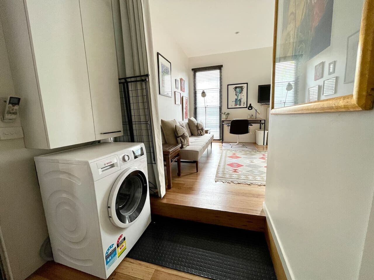 Un espacio habitable compacto con lavadora, sofá, mesa de centro y una pequeña zona de comedor.