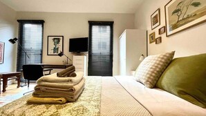 Een slaapkamer met een bed, een bureau, een stoel en een raam met zonwering.