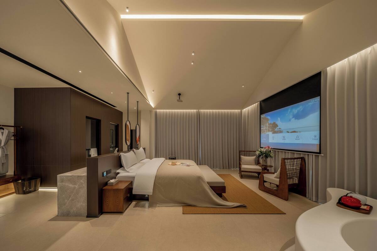 A modern hotel room with a large bed, a TV, a desk, and a bathroom.
