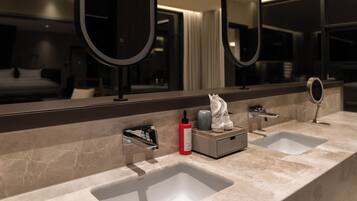 A modern bathroom with two sinks, a large mirror, and a small cabinet.
