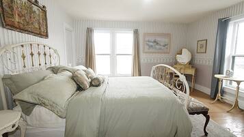 A bedroom with a bed, a dresser, a chair, and a table.
