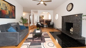Un salon comprenant un canapé, une table basse, une cheminée et un ventilateur de plafond.