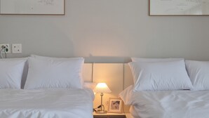 Une chambre d’hôtel avec deux lits, une table de chevet avec une lampe et des tableaux encadrés au mur.