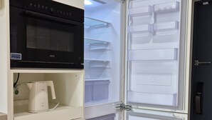 Une cuisine équipée d’un micro-ondes noir, d’une machine à café blanche et d’un réfrigérateur doté de plusieurs compartiments.
