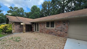 A two-story house with a stone facade, a garage, and a gravel driveway.