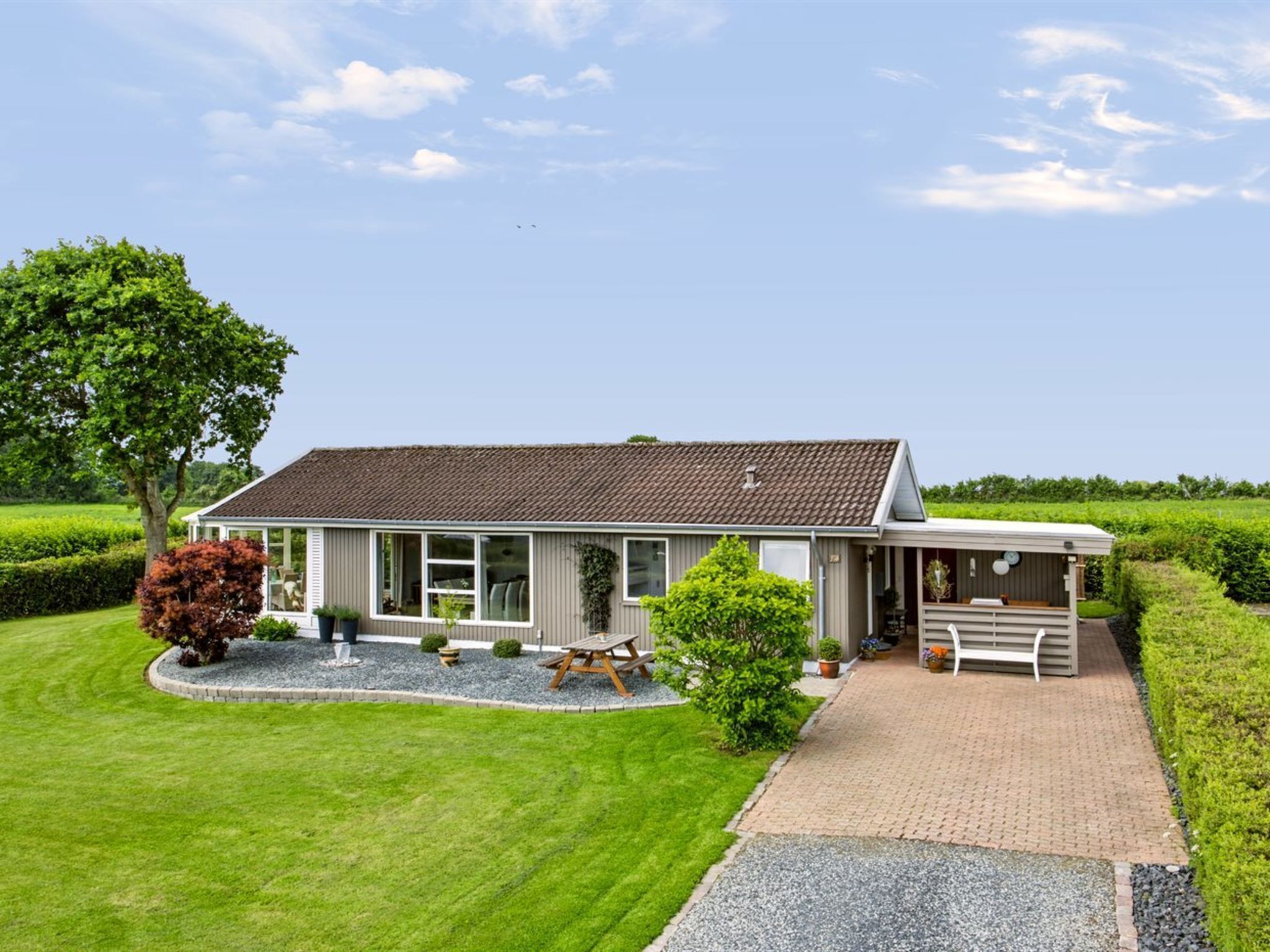 A two-story house with a covered porch, a paved driveway, and a well-maintained lawn.