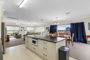 A spacious kitchen with a dining area, large windows, and a view of the outside. - Latitude 39 – Luxury Waterfront Living on Wallaroo Marina (Wallaroo)